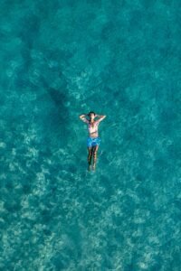 Aerial view of a man relaxing in the turquoise waters of Alaçatı, İzmir, capturing the essence of summer leisure.